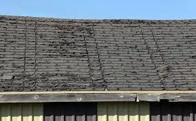 Old damaged roof with cracked shingles and visible wear due to lack of maintenance.