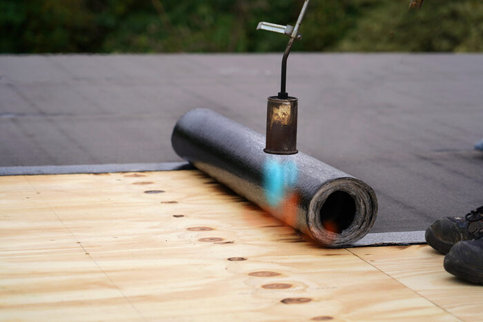 Torch down roofing installation using propane torch on flat roof in New Jersey